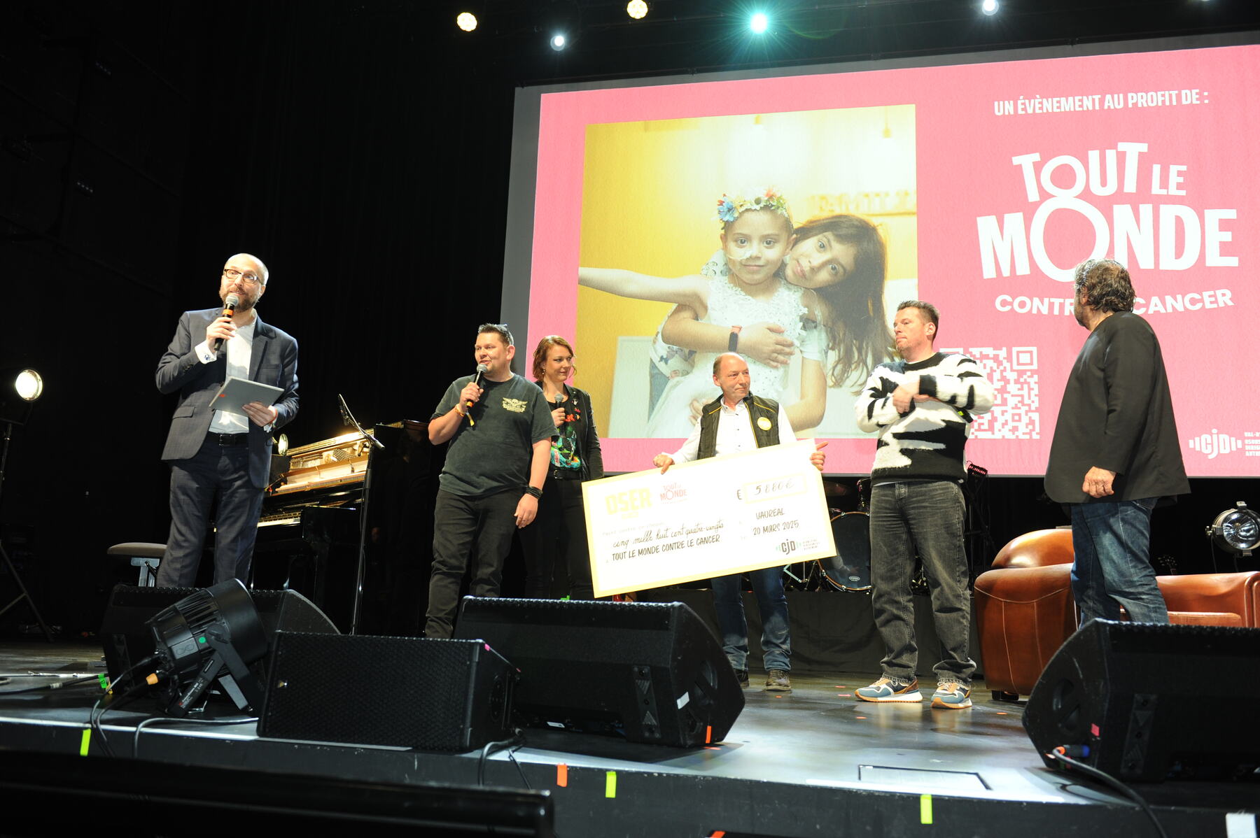 La remise du chèque de 5 880 euros sur scène, devant l'écran de Tout le monde contre le cancer