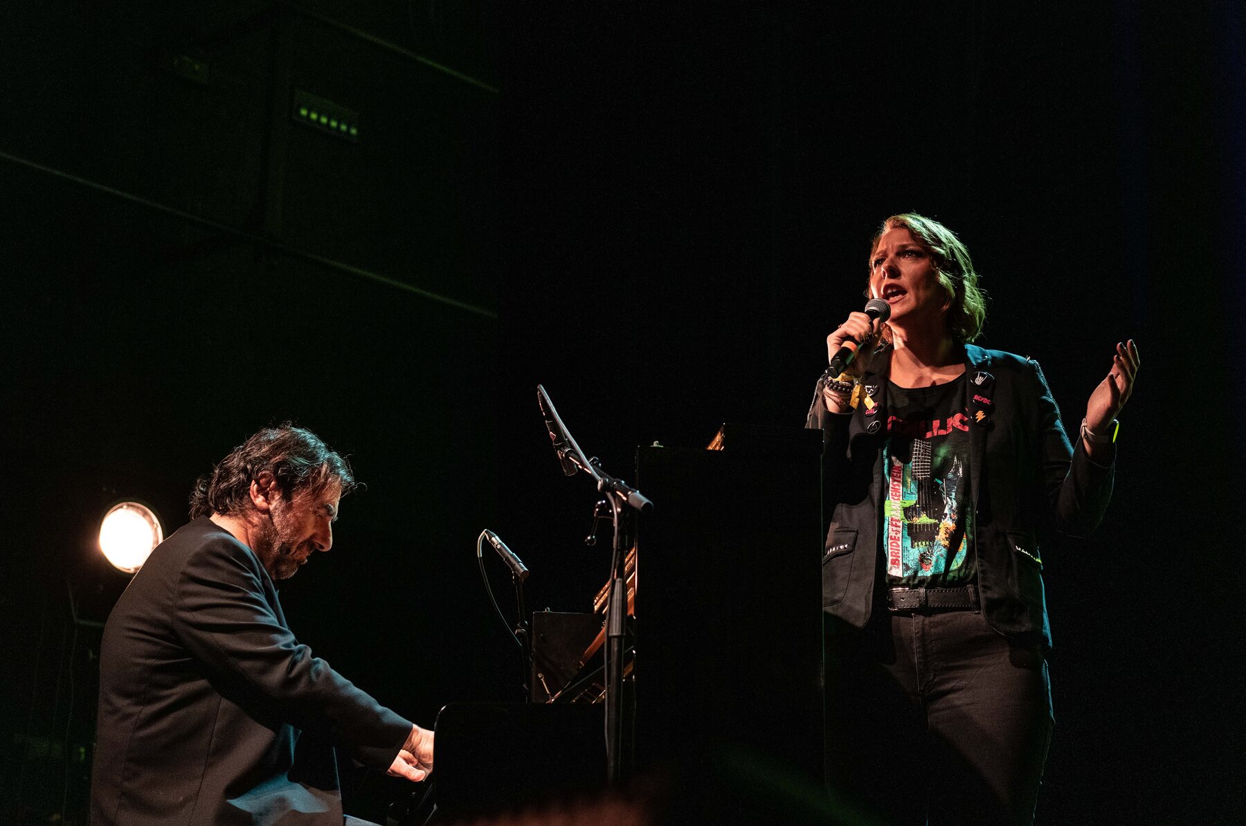André Manoukian au piano, accompagné d'une chanteuse au micro, dans le noir de la scène