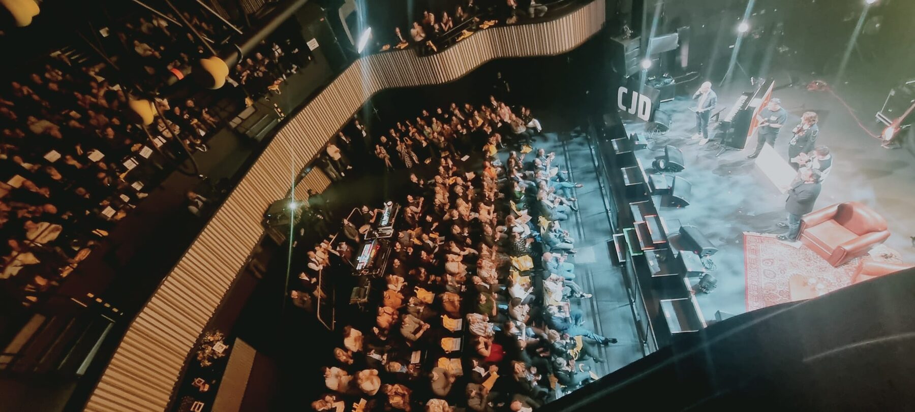 La salle du Forum vue du balcon : les rangs pleins, la scène éclairée et le logo CJD au fond